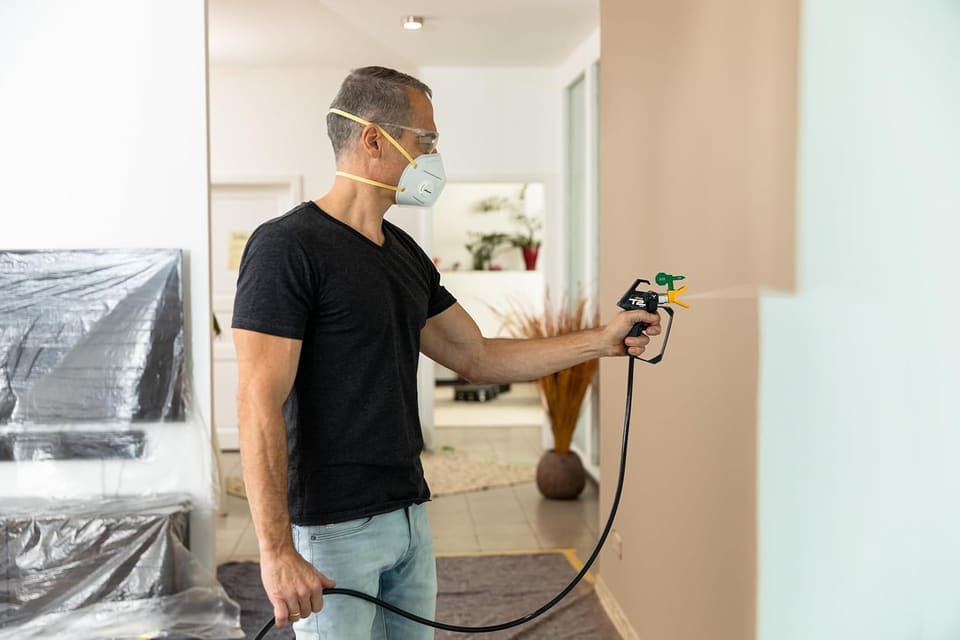 Painter using an airless sprayer indoors