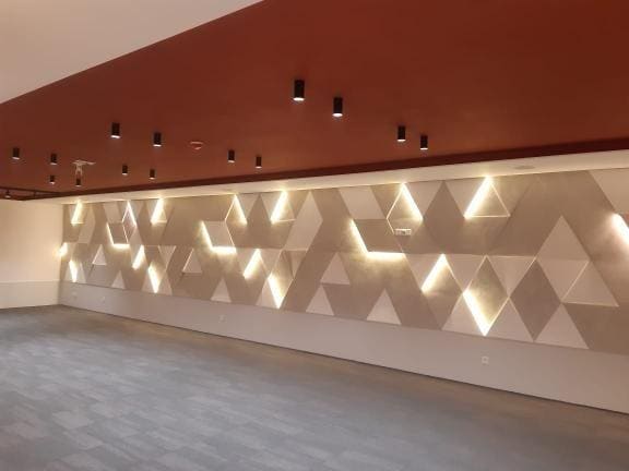 Lit geometric relief wall with rust-effect ceiling